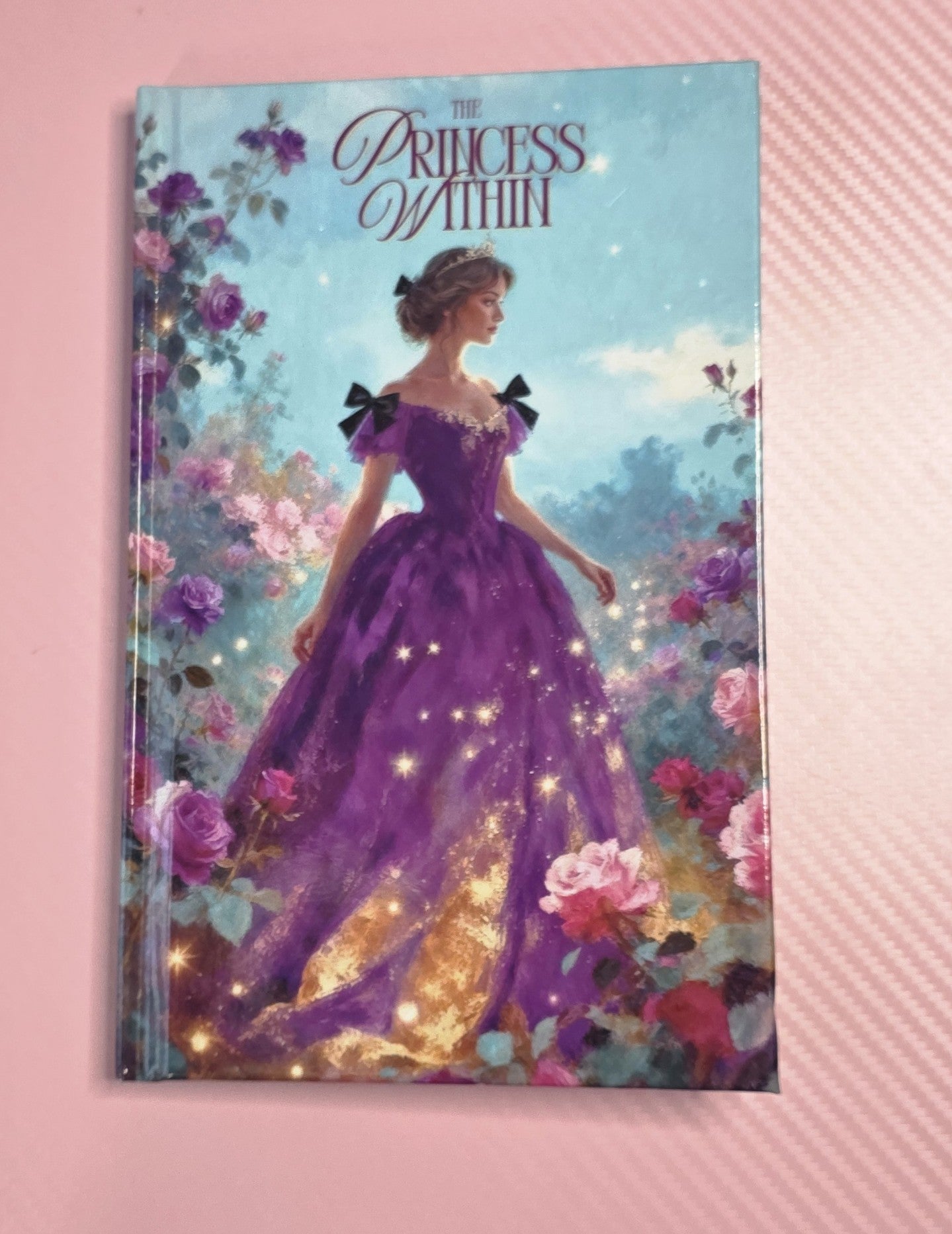 Book titled 'The Princess Within' with a cover illustration of a woman in a purple gown among flowers on a pink background.